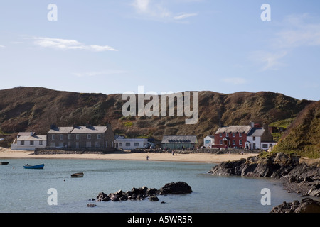 View across calm blue sea to Ty Coch Inn white cottages on beach at Porth Dinllaen village in bay on Lleyn Peninsula Stock Photo