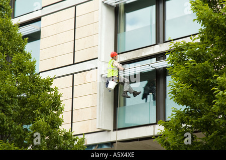 Window cleaner using industrial rope access techniques at work on a hotel building, Manchester, UK Stock Photo