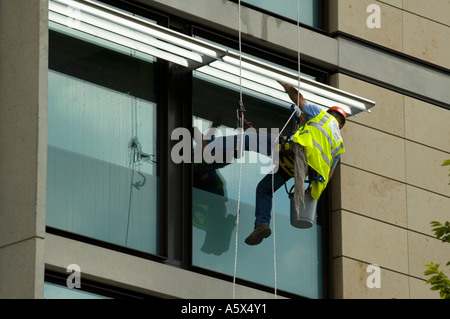 Window cleaner using industrial rope access techniques at work on a hotel building, Manchester, UK Stock Photo