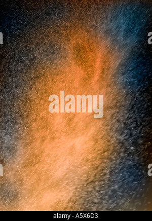 ABSTRACT IMAGE OF ORANGE AND BLUE PARTICLES SWIRLING IN TURBULENT AIR Stock Photo