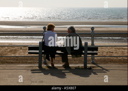 TWO ELDERLY LADIES CHATTING ON BENCH ON GOLDEN MILE BLACKPOOL Stock Photo