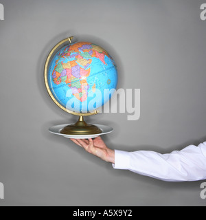 Waiter holding plate with globe. Stock Photo