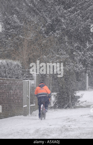 Postman working hard on a snowy winters morning England Stock Photo