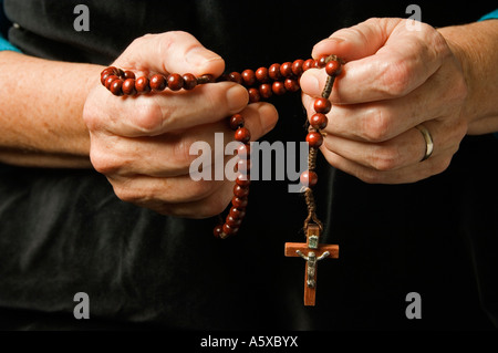 A woman's hand holding rosary beads while praying Stock Photo