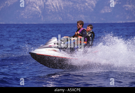 adult male and male child riding personal water craft Stock Photo