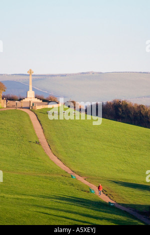 Woman in red coat walking down the hill from the Padstow memorial. Early morning. North Cornwall. UK. Stock Photo