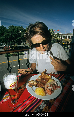 Tourist savouring a guinea pig at the restaurant (Peru). Touriste dégustant un cochon d'Inde au restaurant (Pérou). Stock Photo