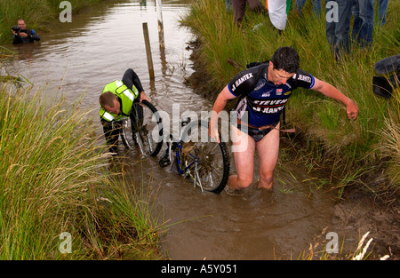 Competitor in annual World Mountain Bike Bog Snorkelling Championships Llanwrtyd Wells Powys removing bike from bog Wales UK Stock Photo