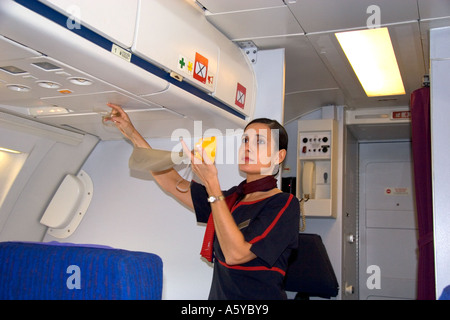 Flight attendant showing how to use an oxygen mask in case of emergency ...