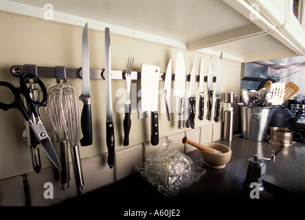 knives and other kitchen implements gleam against the wall of a modern kitchen Stock Photo