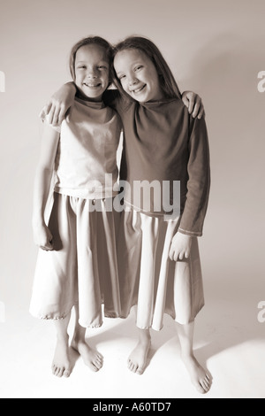Twin sisters aged 10 with arms around each other smiling Stock Photo