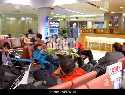 Beijing international Airport, China. Air passengers waiting resting sleeping napping in departure lounge chairs seats Stock Photo