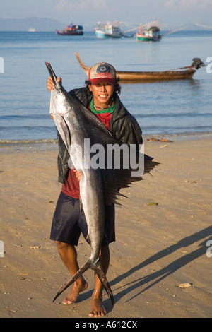 Fisherman holding large swordfish with broken barbs or beak on sandy beach showing morning catch Krabi Province Thailand Stock Photo