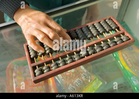 Abacus counting machine calculator. Woman hand using abacus adding subtracting sum on shop counter in Chinese shop, China Stock Photo