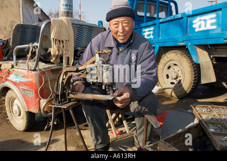 Chinese shoemaker cobbler making shoes with stitching machine and last in farming village of Hui Wen in Shandong Province China Stock Photo