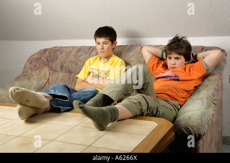 portrait of two young boys glued to the television with their feet on the table Stock Photo