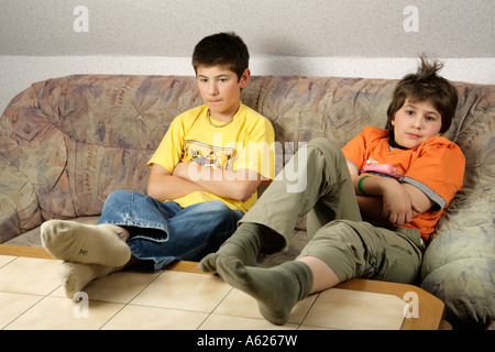 portrait of two young boys glued to the television with their feet on the table Stock Photo