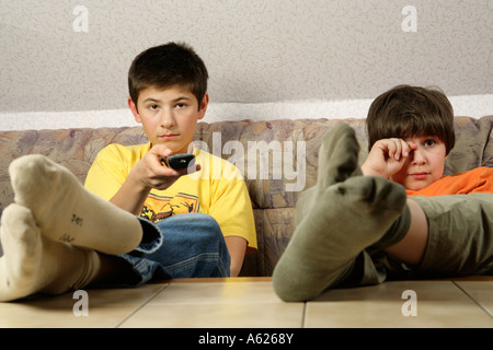 portrait of two young boys glued to the television with their feet on the table Stock Photo