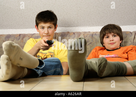 portrait of two young boys glued to the television with their feet on the table Stock Photo