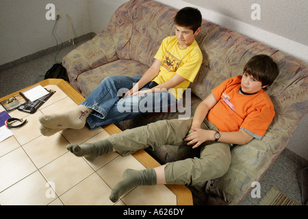 portrait of two young boys glued to the television with their feet on the table Stock Photo