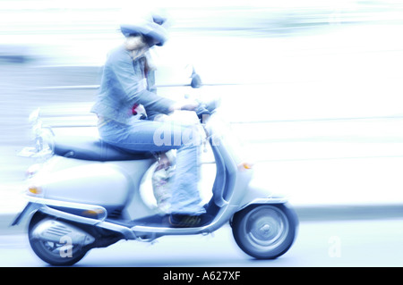 Side profile of woman riding motor scooter Stock Photo