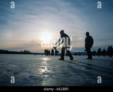 Silhouette of people playing curling on frozen lake, Lake Chiemsee, Upper Bavaria, Bavaria, Germany Stock Photo