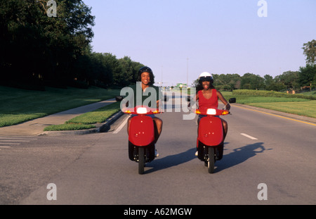 Happy black couple on red mopeds riding with helmets on road these african american couple Stock Photo