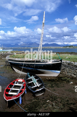grounded wooden boats lying on irelands west coastal foreshore with twelve pins bens mountains in background, Stock Photo