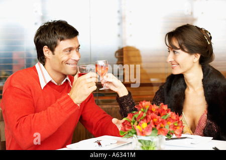 Mid adult couple sitting in a restaurant and toasting with wine glasses Stock Photo
