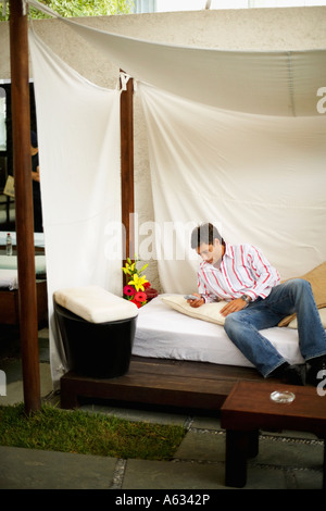 Mid adult man reclining on the bed and using a mobile phone Stock Photo