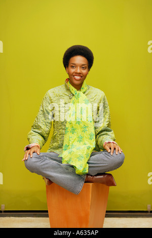 Young woman sitting on a stool and smiling Stock Photo