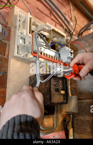 AN ELECTRICIAN REMOVES OLD ELECTRICITY FUSE BOXES AND INSTALLS A MEMERA CONSUMER UNIT UK Stock Photo