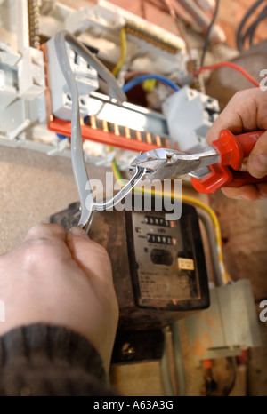 AN ELECTRICIAN REMOVES OLD ELECTRICITY FUSE BOXES AND INSTALLS A MEMERA CONSUMER UNIT UK Stock Photo