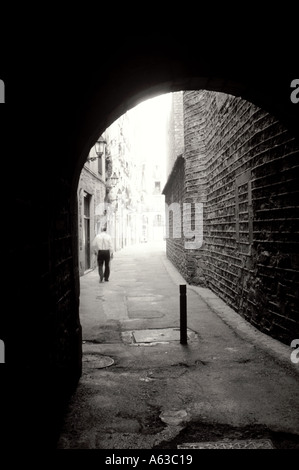 European street through archway with a man walking in the distance Barcelona Spain Stock Photo