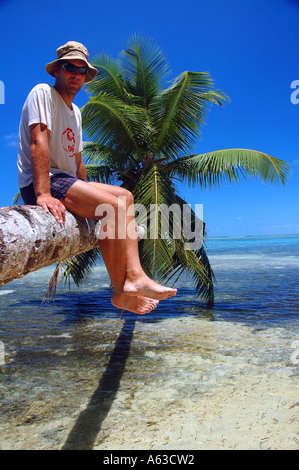 Tourist sitting on reclining palm tree Ile Aux Nattes Nosy Nato Madagascar MR Stock Photo