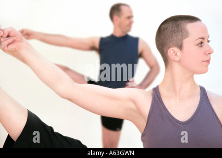 A shaven headed woman holding her leg up in the air in a yoga position Stock Photo