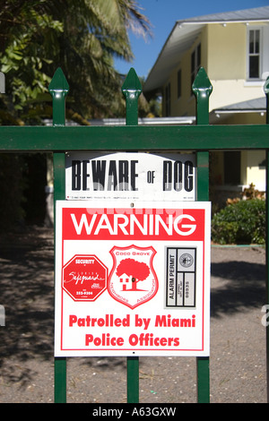 A sign on a gate in Coconut Grove Florida warning that the area is patrolled by police officers and Beware of the Dog Stock Photo