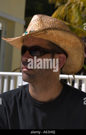 A middle aged man wearing sunglasses and a cowboy hat outside in the bright sunshine Stock Photo