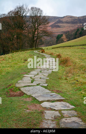 Winding stone flag path leads up through Grindsbrook to Kinder Scout in the Derbyshire Peak District Stock Photo