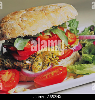 Shredded pesto chicken in a granary bap with tomatoes, lettuce, rocket, sliced red peppers, red onions and toasted pine nuts. Stock Photo