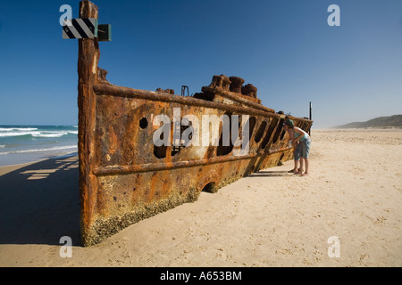 A couple look through the rusted hulk of the Maheno a passenger liner that was blown ashore on Fraser Island by a cyclone Stock Photo