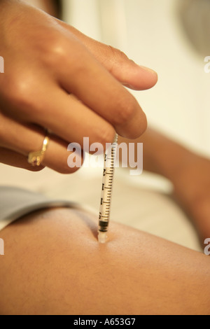 Young girl injects insulin into her thigh because of her diabetes. Stock Photo