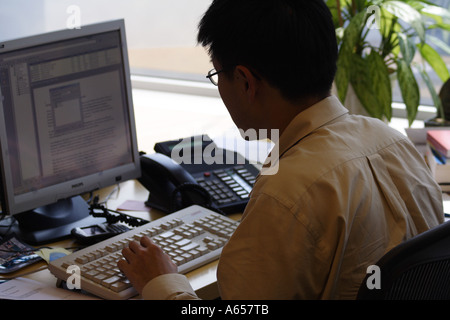 Businessman sitting in front of a computer in the office, Hong Kong, SAR Stock Photo