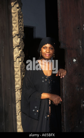 Swahili woman wearing a traditional bui bui standing in a Zanzibar doorway Zanzibar Tanzania Stock Photo