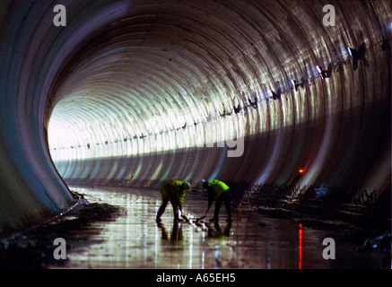 Two Rail Link Engineering construction workers clean the track bed floor at the Country Portal of the  North Downs Tunnel Stock Photo