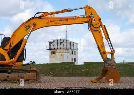 Large yellow JCB digger on shingle beach in front of the old Shoreham Fort, Shoreham by Sea, West Sussex. Stock Photo