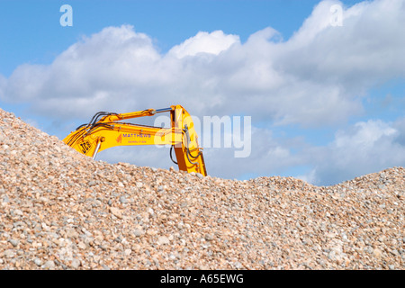 Large yellow JCB digger on beach behind a pile of shingle at Shoreham-by-Sea, West Sussex, England, UK Stock Photo