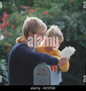 Father and son leaning on mailbox reading letter Stock Photo