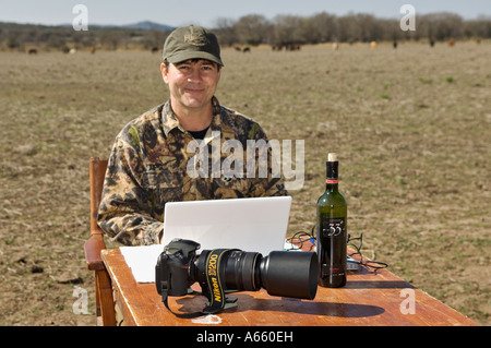Professional Photographer Downloading Digital Photos to Laptop Computer Hard Drive in the Field Near Cordoba Argentina Stock Photo