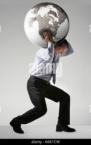 Businessman struggling, carrying globe on shoulders, side view Stock Photo